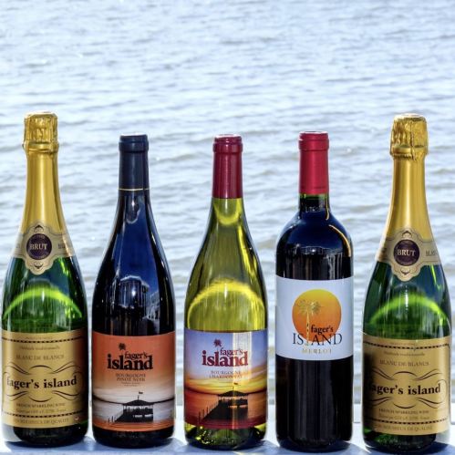 Five bottles of wine from "Fager's Island" displayed against a water backdrop, including sparkling, white, and red varieties.