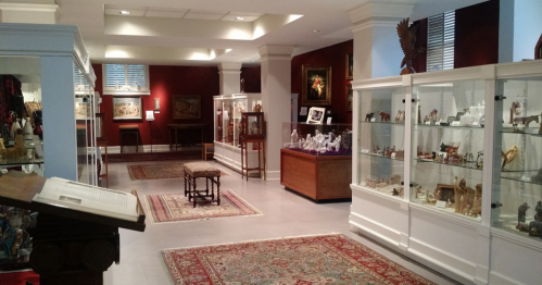 Interior of a museum featuring display cases with artifacts, rugs on the floor, and warm lighting.
