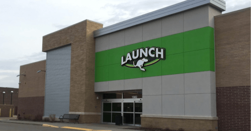 Exterior of a building with a green and gray facade, featuring a sign that reads "LAUNCH."