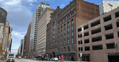 City street view featuring a mix of historic and modern buildings, with a parking garage on the right.