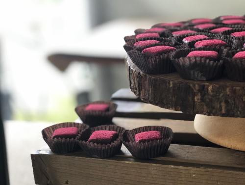A wooden display holds chocolate treats with bright pink centers, arranged neatly on a rustic table.