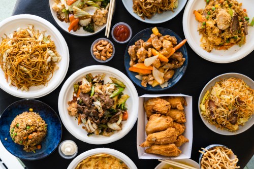 A variety of Asian dishes including noodles, fried rice, chicken, and vegetables arranged on plates.