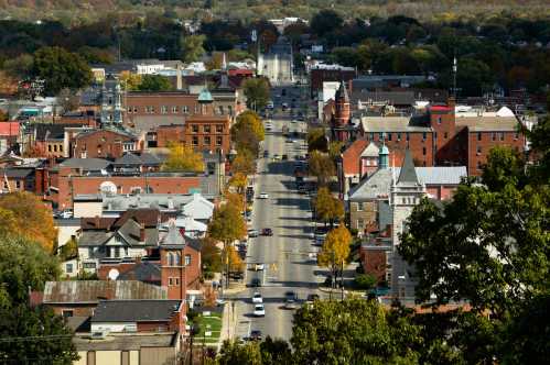 Aerial view of a small town with tree-lined streets, historic buildings, and autumn foliage.