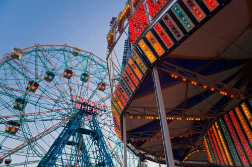 Colorful carnival scene featuring the Wonder Wheel and vibrant lights on a ride at dusk.