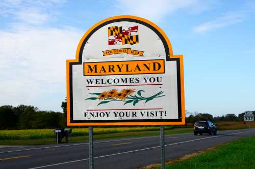 A welcome sign for Maryland featuring the state flag and the text "Maryland Welcomes You! Enjoy Your Visit!"