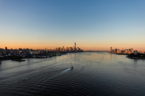 A serene sunset over a city skyline, with a boat gliding through calm waters.