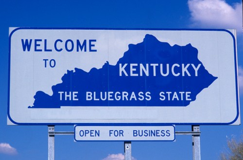 Welcome sign for Kentucky, featuring the state outline and the phrase "The Bluegrass State." Open for business.