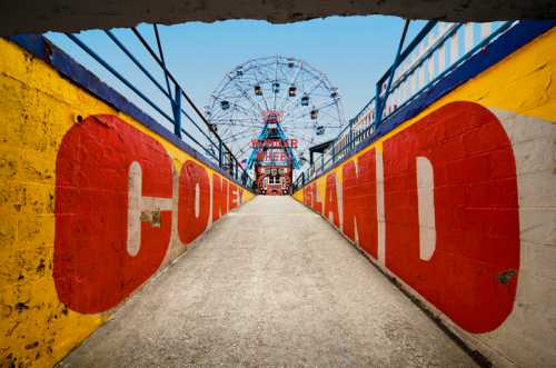 A colorful entrance to Coney Island, featuring a bright mural and a view of the amusement rides in the background.