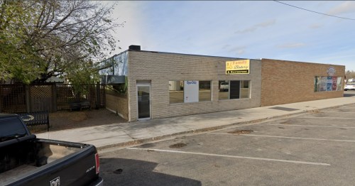 A brick building with large windows and a sign for a family bakery, located on a quiet street.