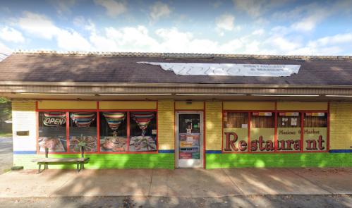 Colorful exterior of a Mexican restaurant with "Open" sign and large windows displaying vibrant decorations.