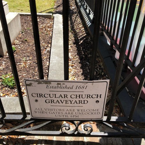Sign at a graveyard entrance reads "Circular Church Graveyard, Established 1681. Visitors welcome when gates are unlocked."