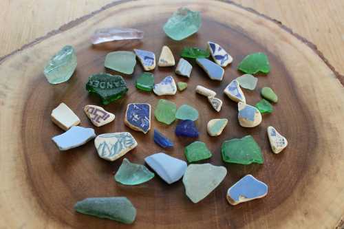 A collection of colorful sea glass and pottery shards arranged on a wooden surface.