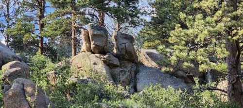 Rock formations surrounded by greenery and trees under a clear blue sky.
