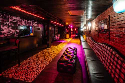 A dimly lit lounge with a patterned carpet, plush seating, and vibrant lighting, creating a cozy atmosphere.