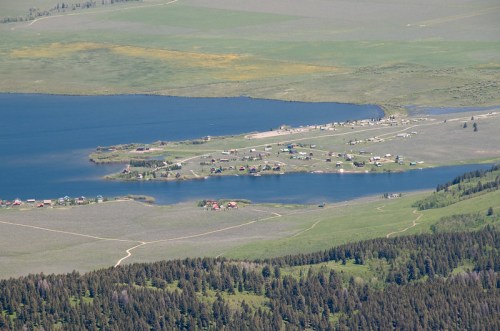 Aerial view of a small lakeside village surrounded by green fields and forests.