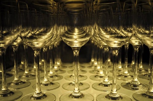 A close-up of numerous wine glasses arranged in a symmetrical pattern, illuminated with a warm glow.