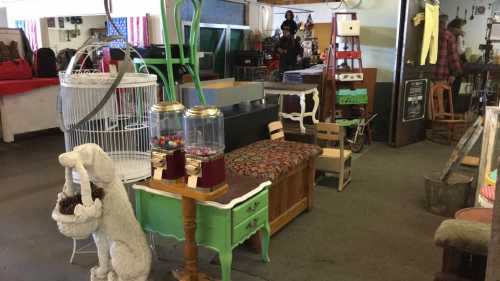 A vintage shop interior featuring eclectic furniture, a white dog statue, and colorful decor items.