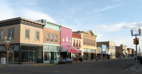 A street view of a small town with colorful storefronts and a clear blue sky.