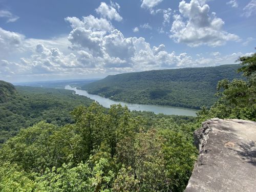A scenic view of a river winding through lush green hills under a partly cloudy sky.