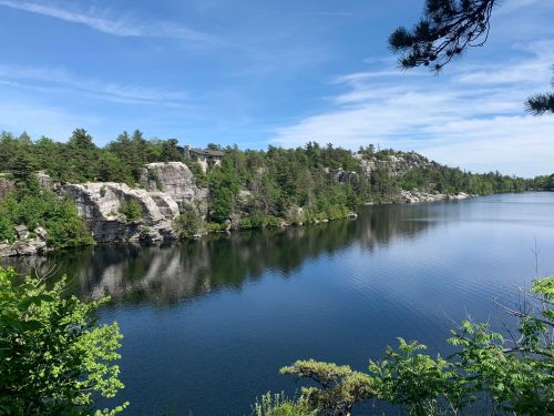 A serene lake surrounded by rocky cliffs and lush greenery under a clear blue sky.
