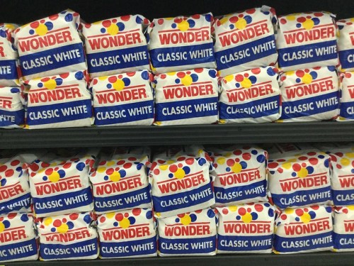 Shelves stacked with packages of Wonder Classic White bread, featuring colorful polka dots and bold branding.