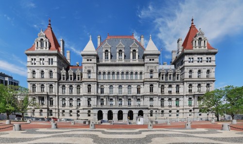 Historic building with ornate architecture, featuring multiple towers and a blue sky backdrop.