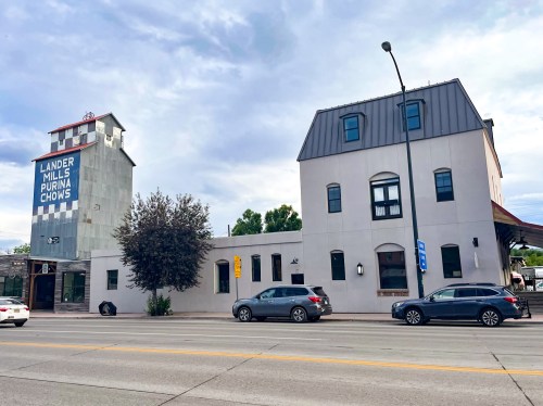 A street view of a building with a sign reading "Lander Mills Purina Chows" next to a modern structure.