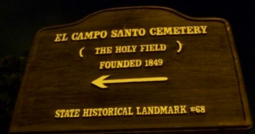 Sign for El Campo Santo Cemetery, founded in 1849, indicating it's a state historical landmark. Arrow points left.