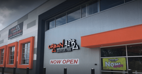 Exterior of Urban Air Adventure Park building with a "Now Open" sign. Bright colors and modern design.