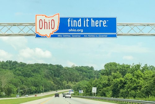 Blue highway sign for Ohio with the text "find it here" and website, featuring names of the governor and lieutenant governor.