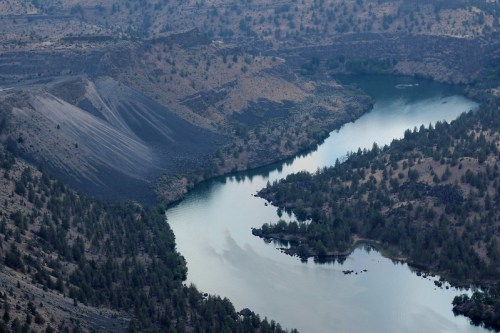 Aerial view of a winding river surrounded by rocky terrain and sparse vegetation.