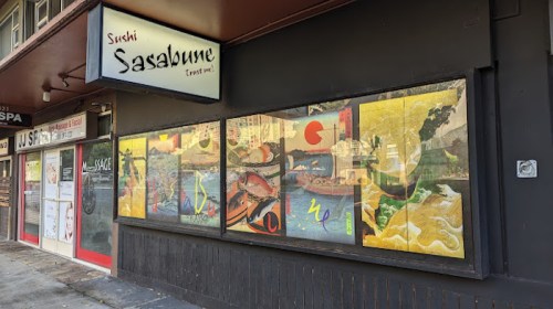 Exterior of Sushi Sasabune restaurant, featuring colorful window art and a sign above the entrance.