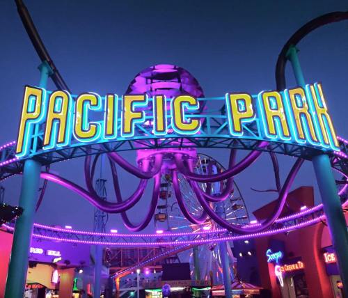 Neon sign of Pacific Park illuminated at dusk, featuring an octopus design and vibrant colors.
