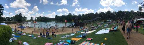 A sunny beach scene with people swimming, lounging on towels, and enjoying a lake surrounded by trees and clouds.