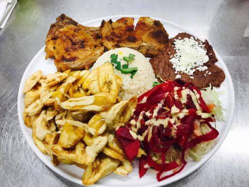A plate of food featuring grilled meat, rice, refried beans, fried plantains, and a colorful salad.