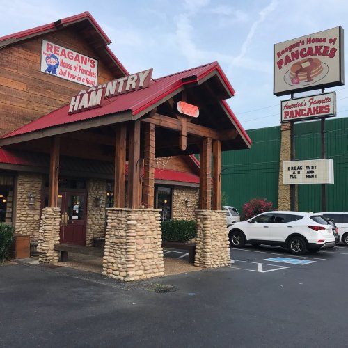 Exterior of Reagan's House of Pancakes, featuring a wooden facade, stone pillars, and a red roof. Parking lot visible.