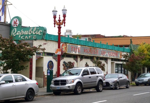 A street view of Republic Café and The House of Louie, featuring colorful signage and parked cars.