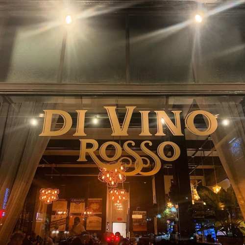 Sign for "Di Vino Rosso" restaurant, illuminated with warm lights, showcasing a cozy dining atmosphere.