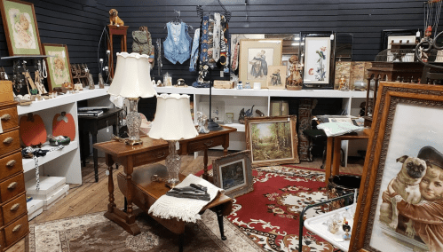 A cozy antique shop filled with vintage items, including lamps, artwork, and decorative pieces on display.