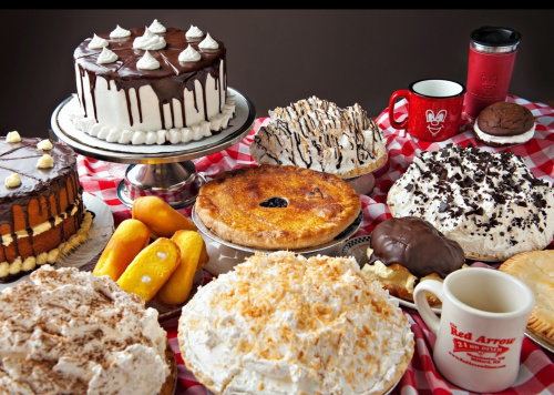 A variety of desserts including cakes, pies, and pastries displayed on a checkered tablecloth.
