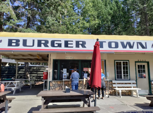 A small burger stand named "Burger Town" with outdoor seating and customers ordering at the window.