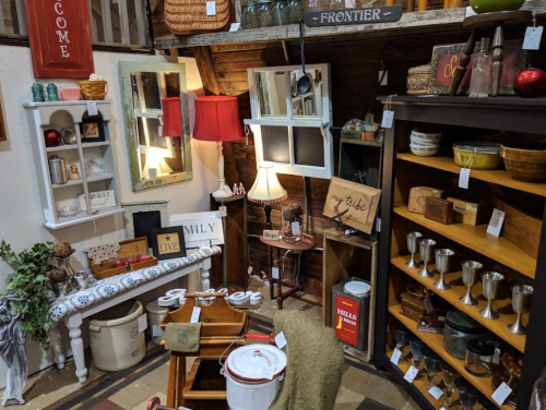 A cozy vintage shop display featuring rustic decor, wooden shelves, and various home goods.