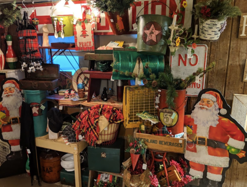 A festive display featuring vintage Christmas decorations, including Santa figures, colorful containers, and holiday-themed items.