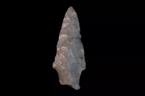 A pointed stone tool with a rough texture, resembling a spearhead, set against a black background.