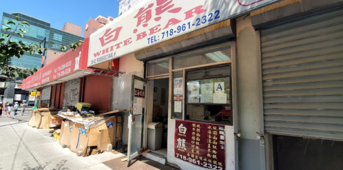 Exterior of White Bear restaurant, featuring a sign and entrance, with boxes and trash nearby on a city street.
