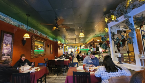 Cozy restaurant interior with tables set for dining, warm lighting, and patrons enjoying their meals.