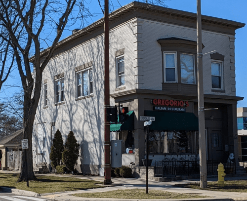 A two-story building with a green awning, labeled "Grigorio's Italian Restaurant," at a street corner.