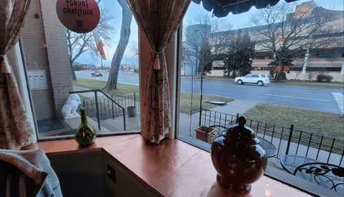 View from a restaurant window showing a street, trees, and a decorative vase on the windowsill.