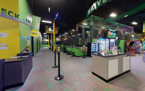 Interior of a vibrant entertainment center with check-in area, arcade games, and colorful decor.