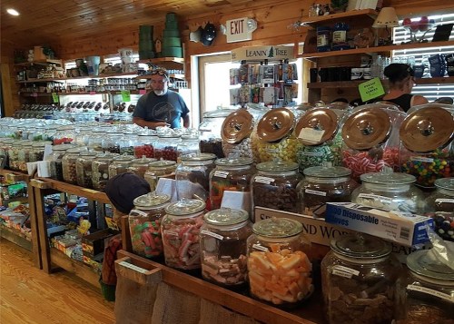 A colorful candy shop filled with jars of various sweets and treats, with customers browsing the selection.